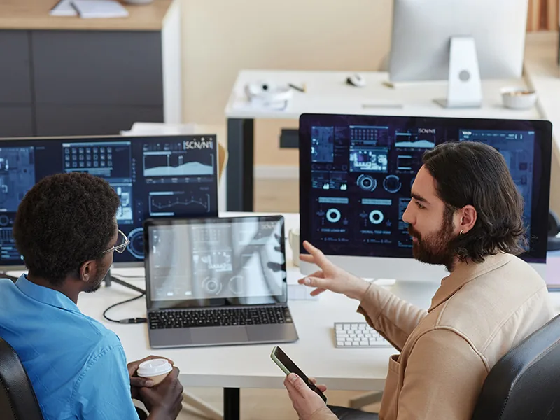 Two engineers reviewing system monitoring on their screens