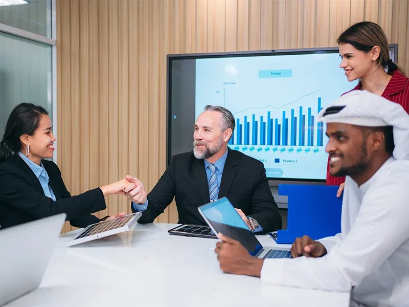 A financial services team meeting in front of a reporting dashboard