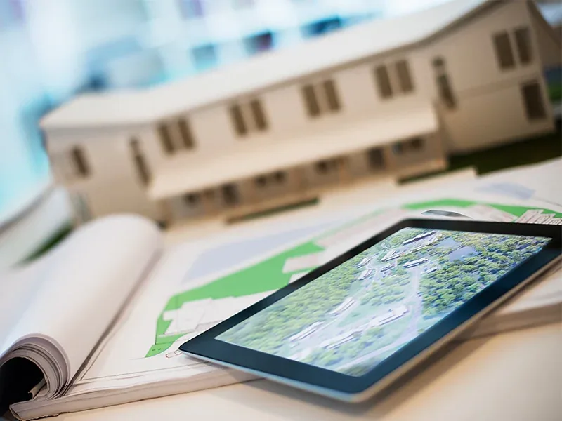 An architectural model of a building beside a tablet showing a site map